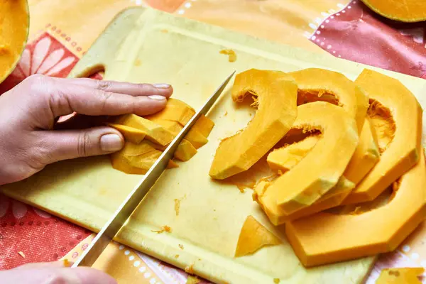 Le mani femminili tagliano la zucca in cucina — Foto Stock