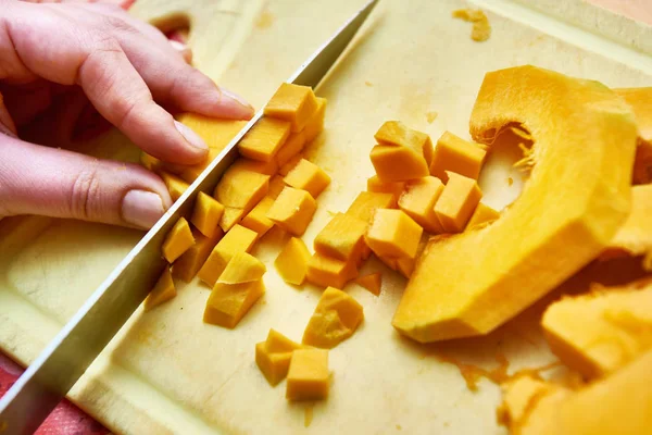 Le mani femminili tagliano la zucca in cucina — Foto Stock