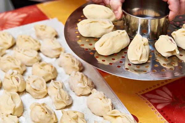 Womens hands with dumplings manti and platform for cooking — Stock Photo, Image