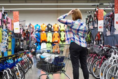Woman chooses the goods in sports store clipart
