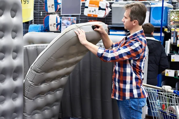 Man chooses inflatable tourist sleeping pad in sports shop — Stock Photo, Image