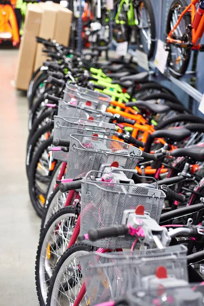 Ряд новых велосипедов с корзинами в магазине — стоковое фото
