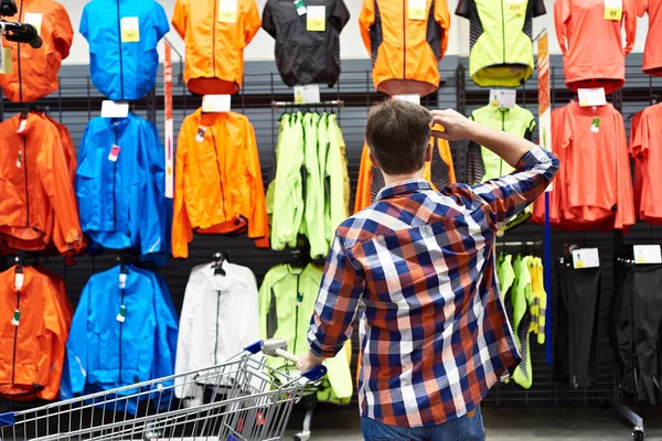 Man chooses sports clothes in store — Stock Photo, Image