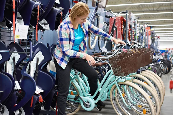 Mulher escolhe bicicleta na loja — Fotografia de Stock