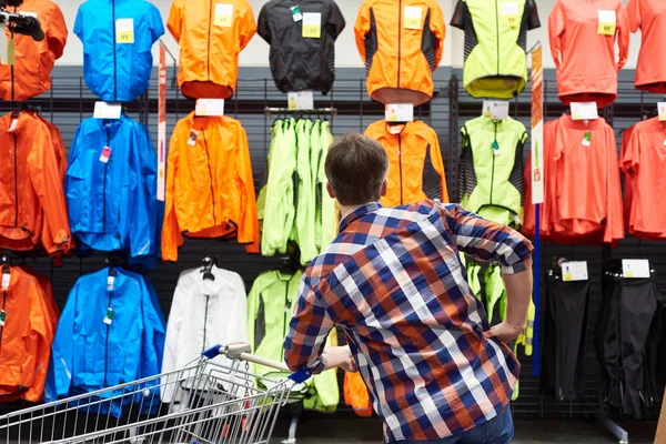 Man chooses sports clothes in store — Stock Photo, Image