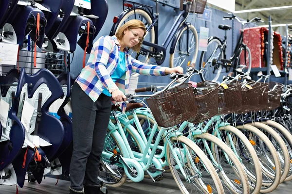 Vrouw kiest fiets in de winkel — Stockfoto