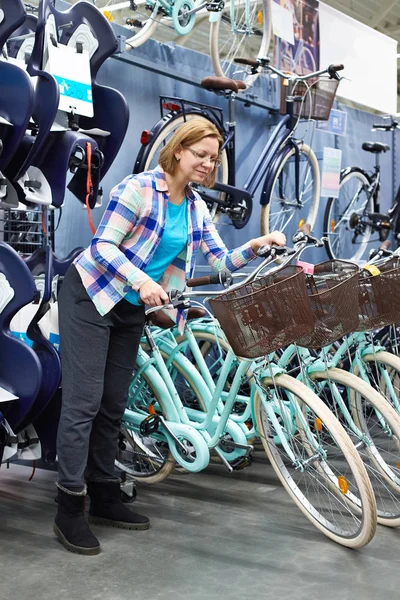 Mulher escolhe bicicleta na loja — Fotografia de Stock