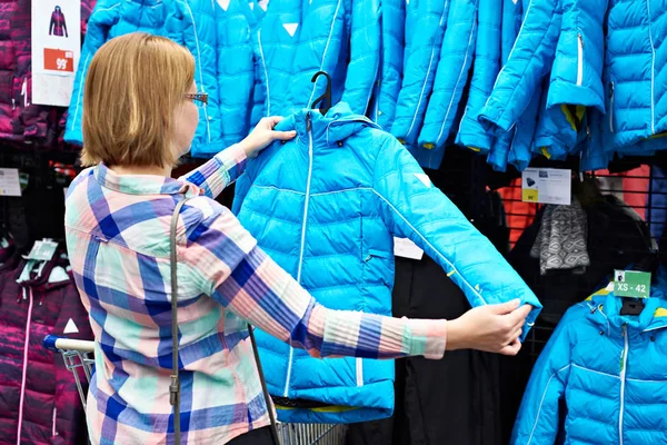 Kobieta wybiera kurtka zimowa w sklepie — Zdjęcie stockowe