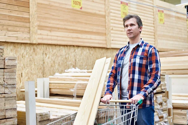 L'homme choisit et achète des planches en bois en magasin — Photo