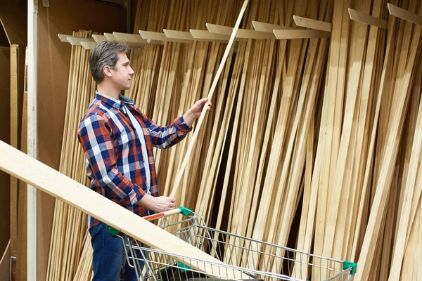 L'homme choisit et achète des planches en bois en magasin — Photo