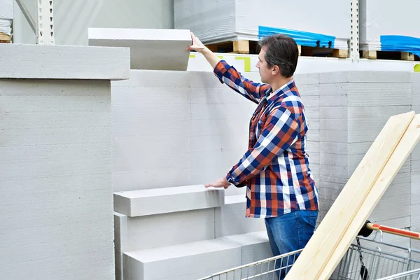 Człowiek wybiera i kupuje betonowe cegły piankowe w sklepie — Zdjęcie stockowe