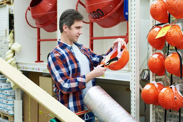 Man chooses and buys construction helmet in store — Stock Photo, Image