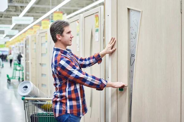 Чоловік вибирає дерев'яні двері в будівельному магазині — стокове фото