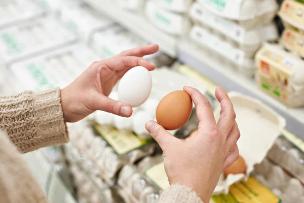 Mains de femme aux œufs blancs et bruns en magasin — Photo
