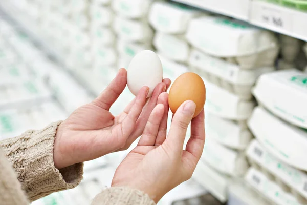 Mãos de mulher com ovos brancos e castanhos na loja — Fotografia de Stock