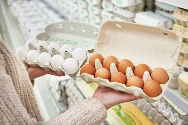 Femme avec des paquets d'œufs blancs et bruns en magasin — Photo