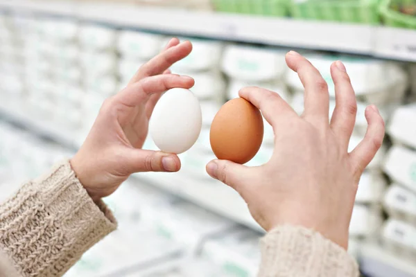 Mains de femme aux œufs blancs et bruns en magasin — Photo