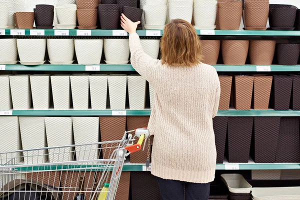 Vrouw koper selecteert bloempotten in winkel — Stockfoto