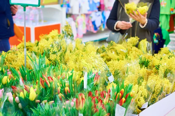 Mujer compra flores tulipanes y mimosa en la tienda — Foto de Stock