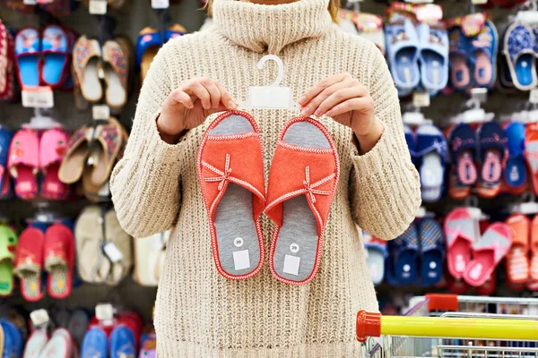 Vrouw klant kiest huis slippers in winkel — Stockfoto
