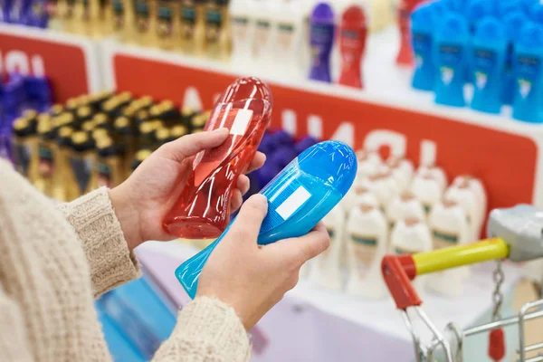 Žena kupující zvolí šampon v obchodě — Stock fotografie