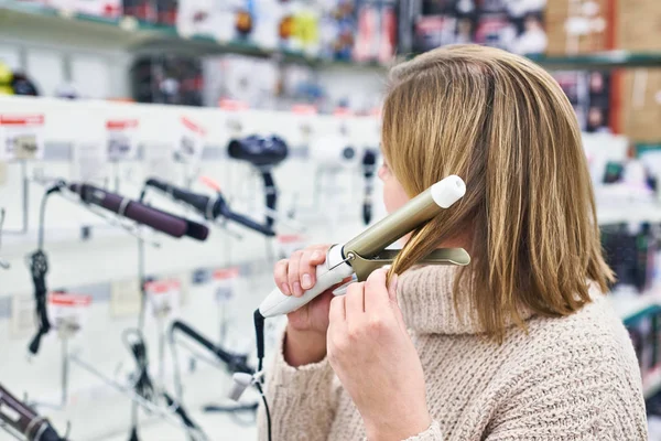 Vrouw selecteert elektrische krultangen in winkel — Stockfoto