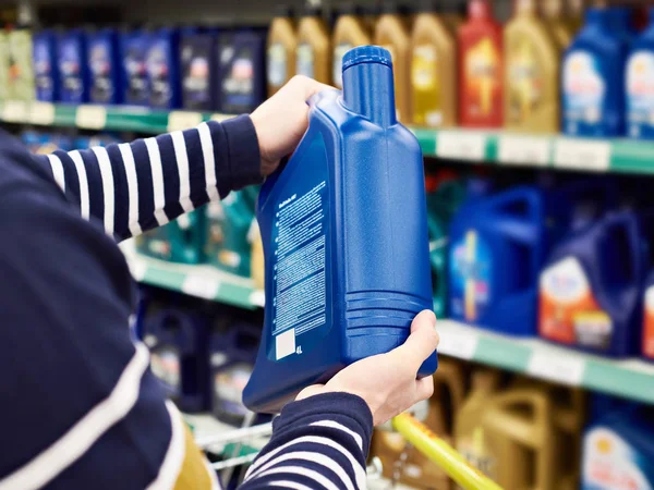 Hombre comprador elige aceite para motor de coche en la tienda —  Fotos de Stock