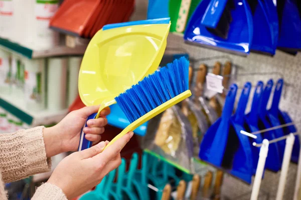 Женские руки с чистящей щеткой и совок в магазине — стоковое фото