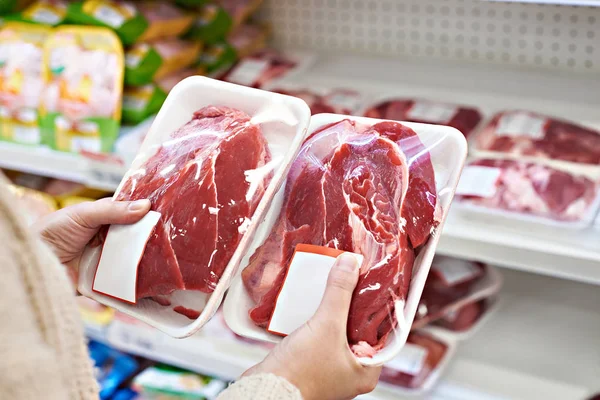 Руки покупця з яловичими м'ясними пакетами на продуктовому — стокове фото