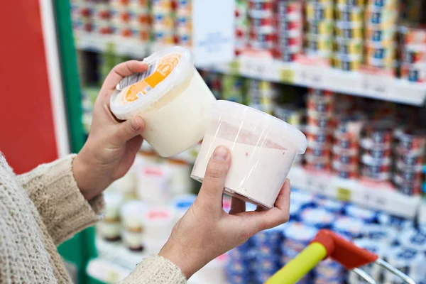 Mãos de comprador com frascos de iogurte de plástico no supermercado — Fotografia de Stock