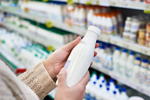 Buyer hands with bottle of milk at grocery — Stock Photo, Image