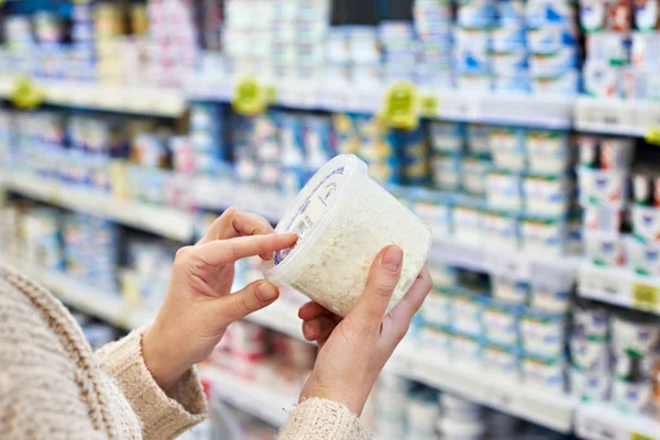 Mãos de comprador com queijo cottage no supermercado — Fotografia de Stock