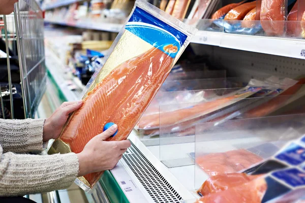 Vrouw koopt licht gezouten rode vis in opslag — Stockfoto