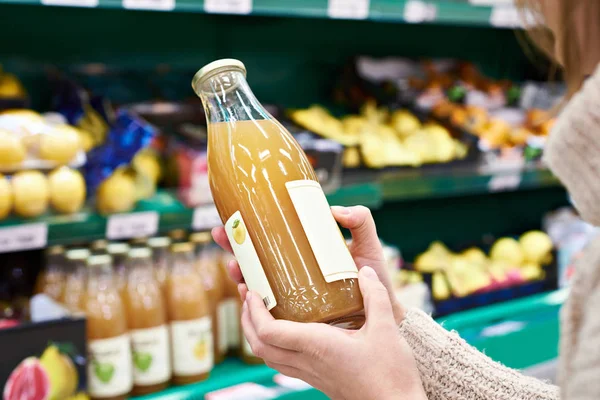 Руки с бутылкой свежего яблочного сока — стоковое фото