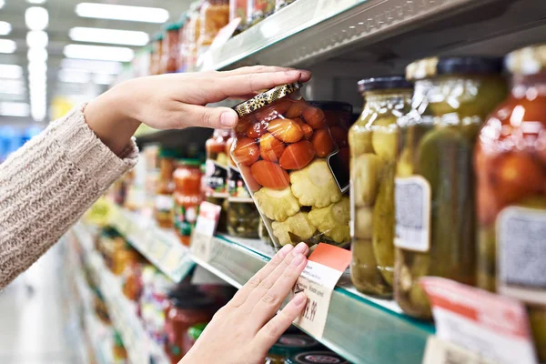 Buyer hands with jar of salted tomatoes and squash in store — Stock Photo, Image