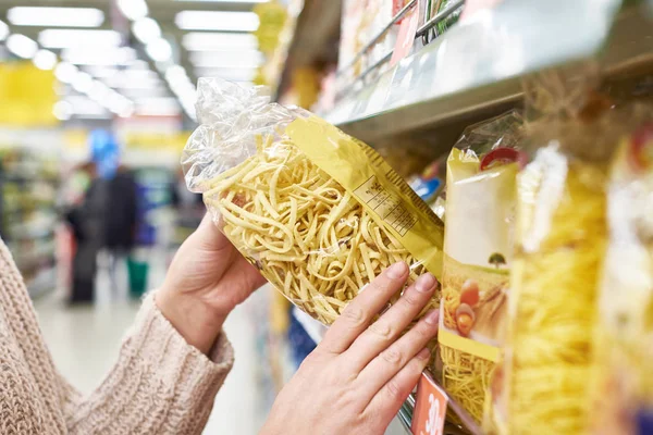 Pack of pasta in hands of buyer at store — Stock Photo, Image