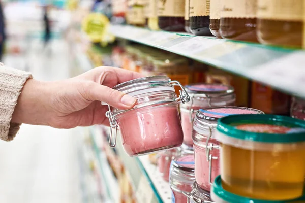 Hand mit Dose Honigsouffle mit Himbeeren im Geschäft — Stockfoto