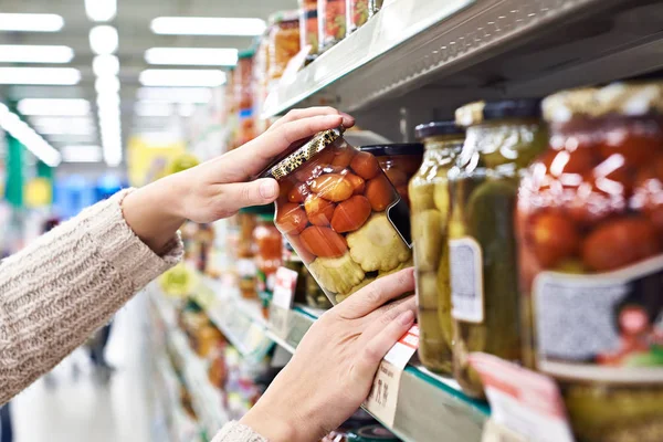 Acheteur mains avec pot de tomates salées et courges en magasin — Photo