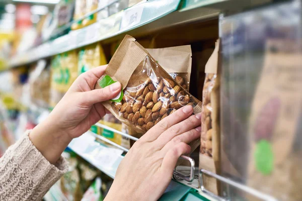 Handen met verpakking van amandel noten in winkel — Stockfoto