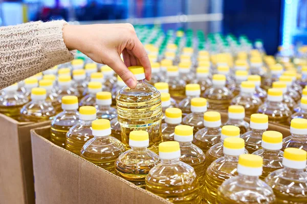 Hand with sunflower oil packaging in store — Stock Photo, Image