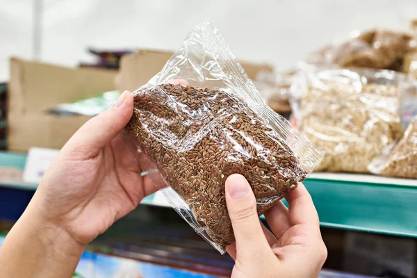 Руки с семенами льна для еды в магазине — стоковое фото