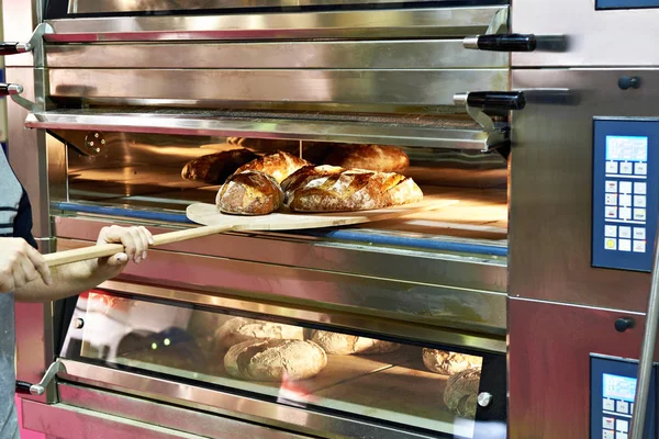 El hombre está horneando pan en el horno — Foto de Stock