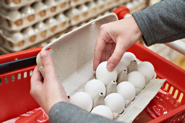 Руки з пакетами білих яєць в магазині — стокове фото