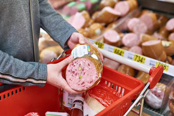 Покупатель с колбасой в корзине в магазине — стоковое фото