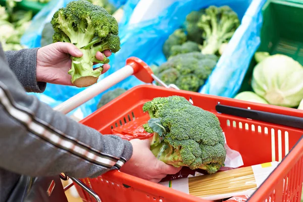Vrouw koopt broccoli in winkel — Stockfoto