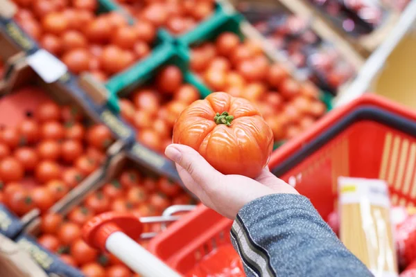 Tomato in hand of buyer at grocery store — Stock Photo, Image