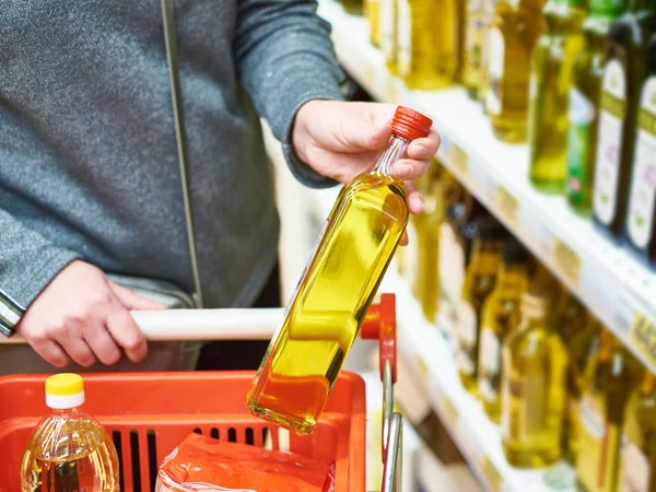 Bottle of olive oil in hand buyer at grocery — Stock Photo, Image