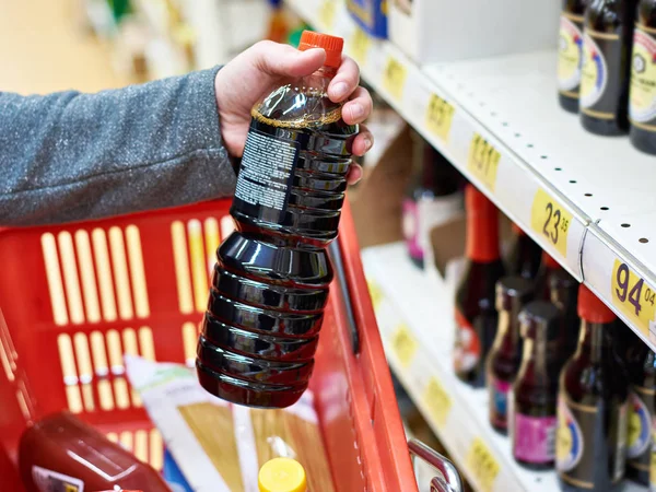 Botella de salsa de soja en la mano comprador en la tienda de comestibles —  Fotos de Stock