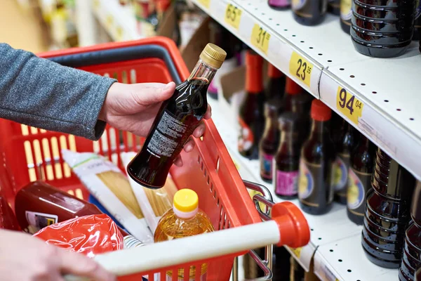 Sojasaus fles in de hand koper in supermarkt — Stockfoto