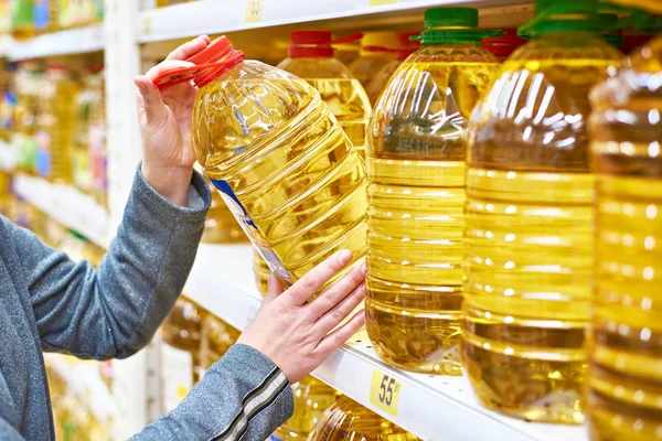 Grote fles olijfolie in hand koper bij supermarkt — Stockfoto